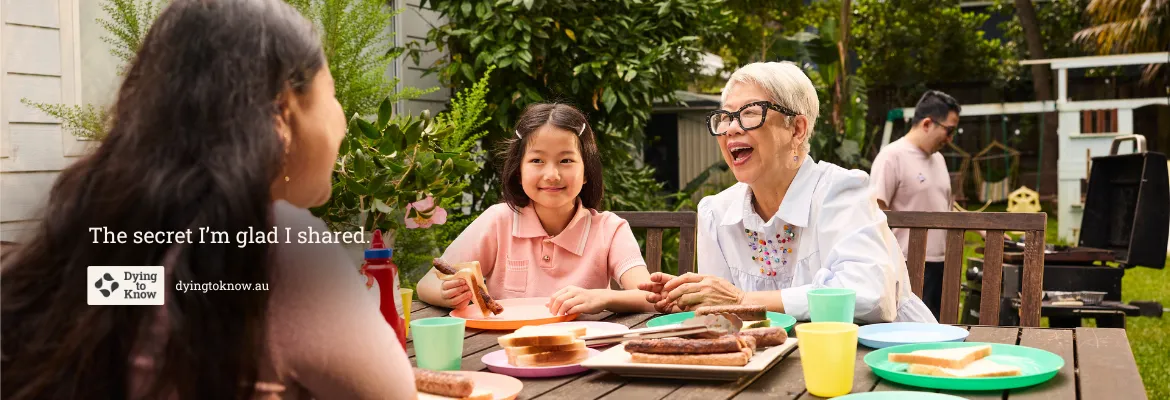 Three generations of a family sharing a meal at a backyard barbecue.